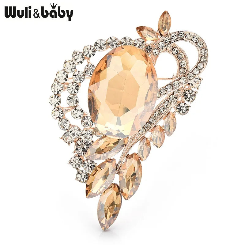 Elegant brooch with a central orange gemstone and surrounding crystals on a white background, featuring the brand 'Wuli & baby'.